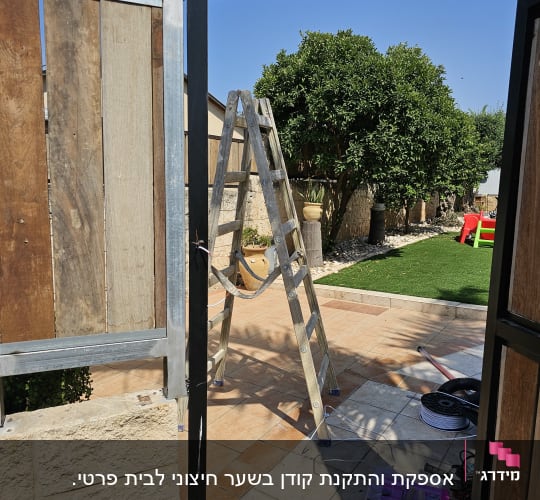 התקנת אינטרקום על עמוד מתכת ליד שער עץ